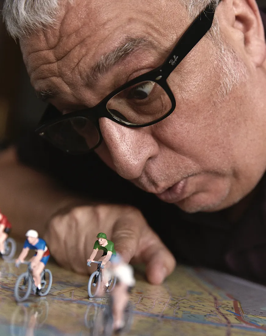 Leo Harlem jugando con sus ciclistas de colección sobre un mapa de París.