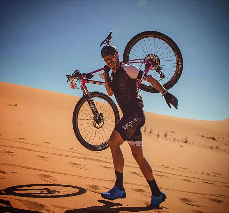 Valentí Sanjuan con su bicicleta a cuestas en las dunas del desierto.