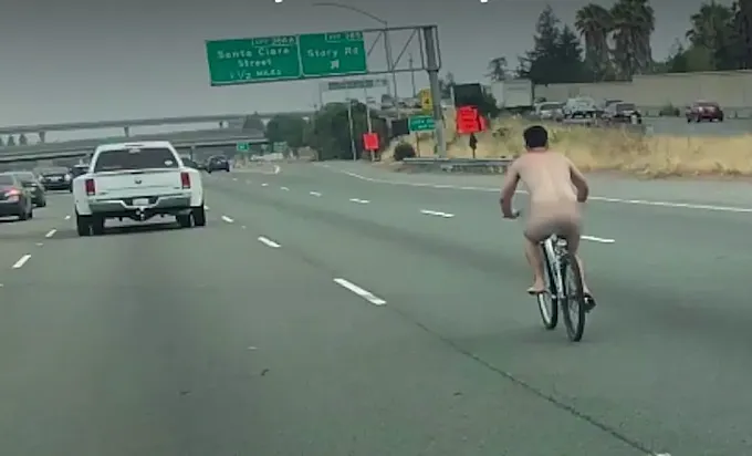 En bicicleta, desnudo y circulando por la autopista